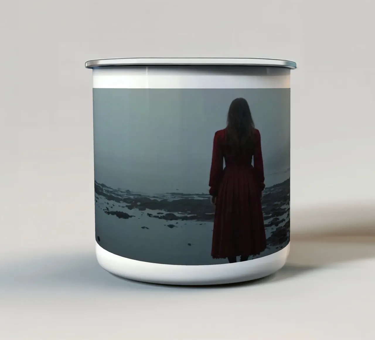 Una donna con un vestito rosso sta in piedi, contemplativa, vicino alla nebbia. tazza in smalto da DesignDoodle