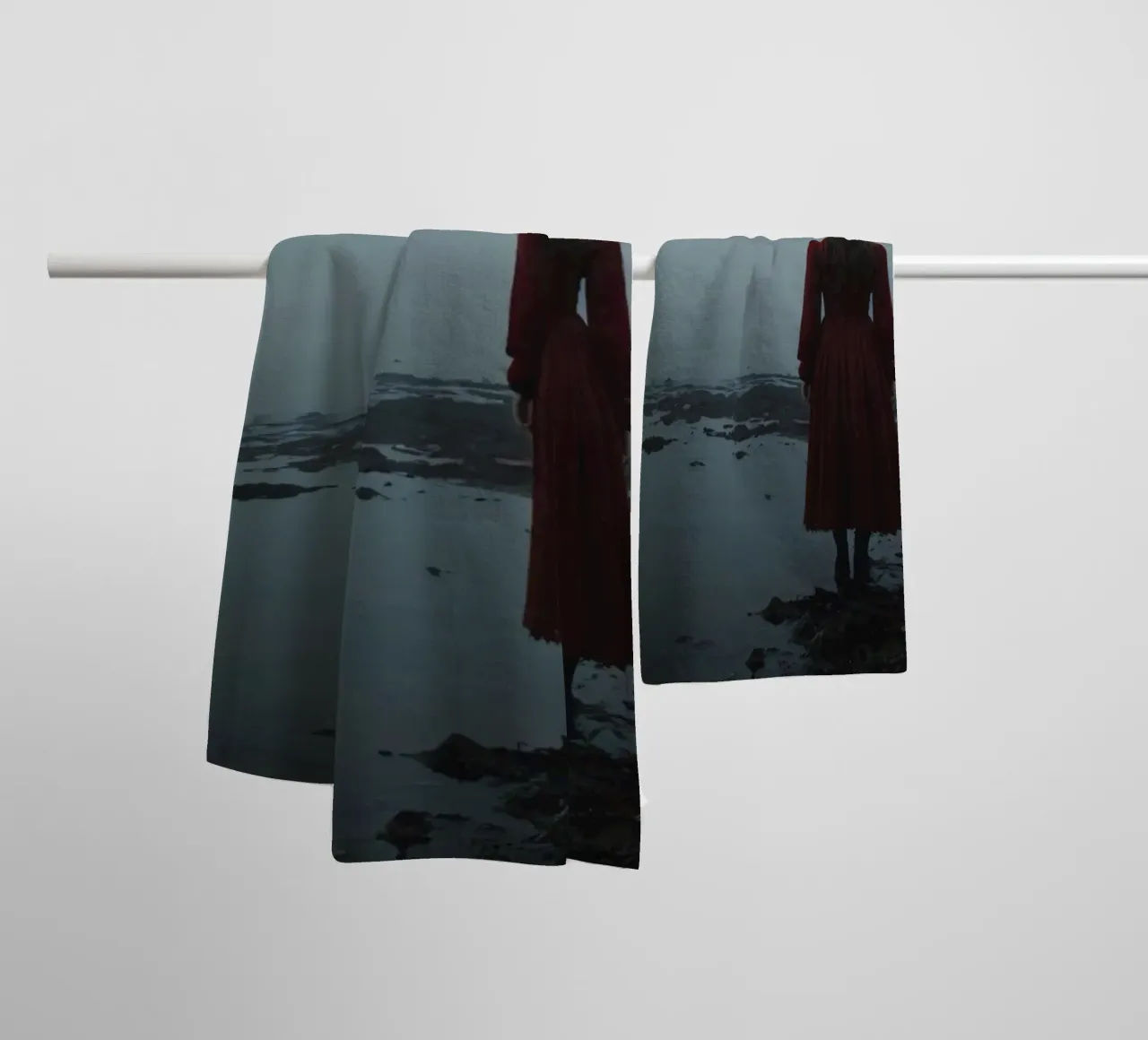 Une femme vêtue d'une robe rouge se tient debout, contemplative, au bord d'une rivière brumeuse. serviette de bain de DesignDoodle