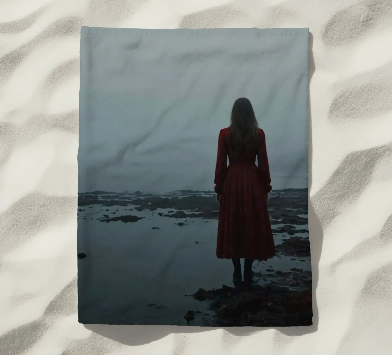 Una donna con un vestito rosso sta in piedi, contemplativa, vicino alla nebbia. telo mare da DesignDoodle
