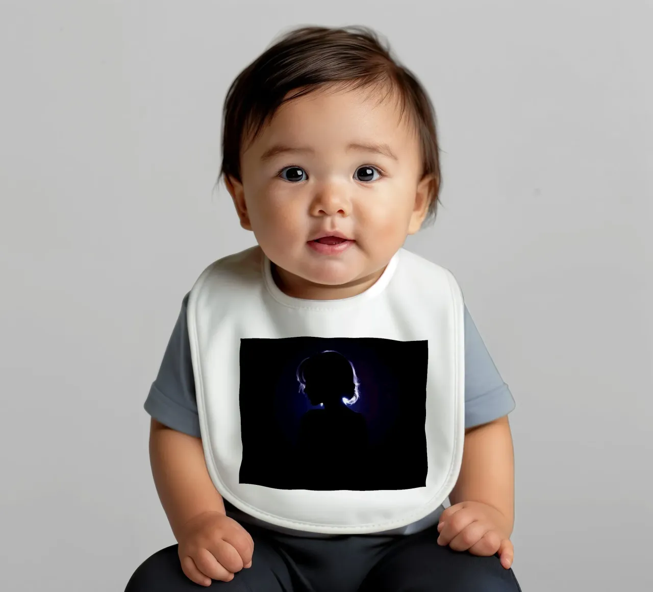 Silhouette of a child against a dark background illuminated baby bib by DesignDoodle
