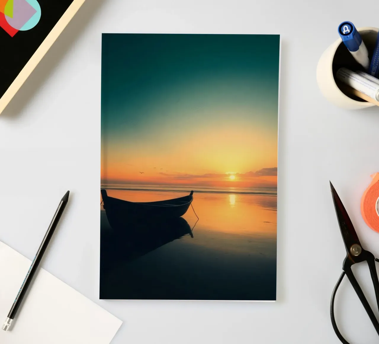 Silhouetted boat resting on calm water at sunset with vibran notebook by DesignDoodle