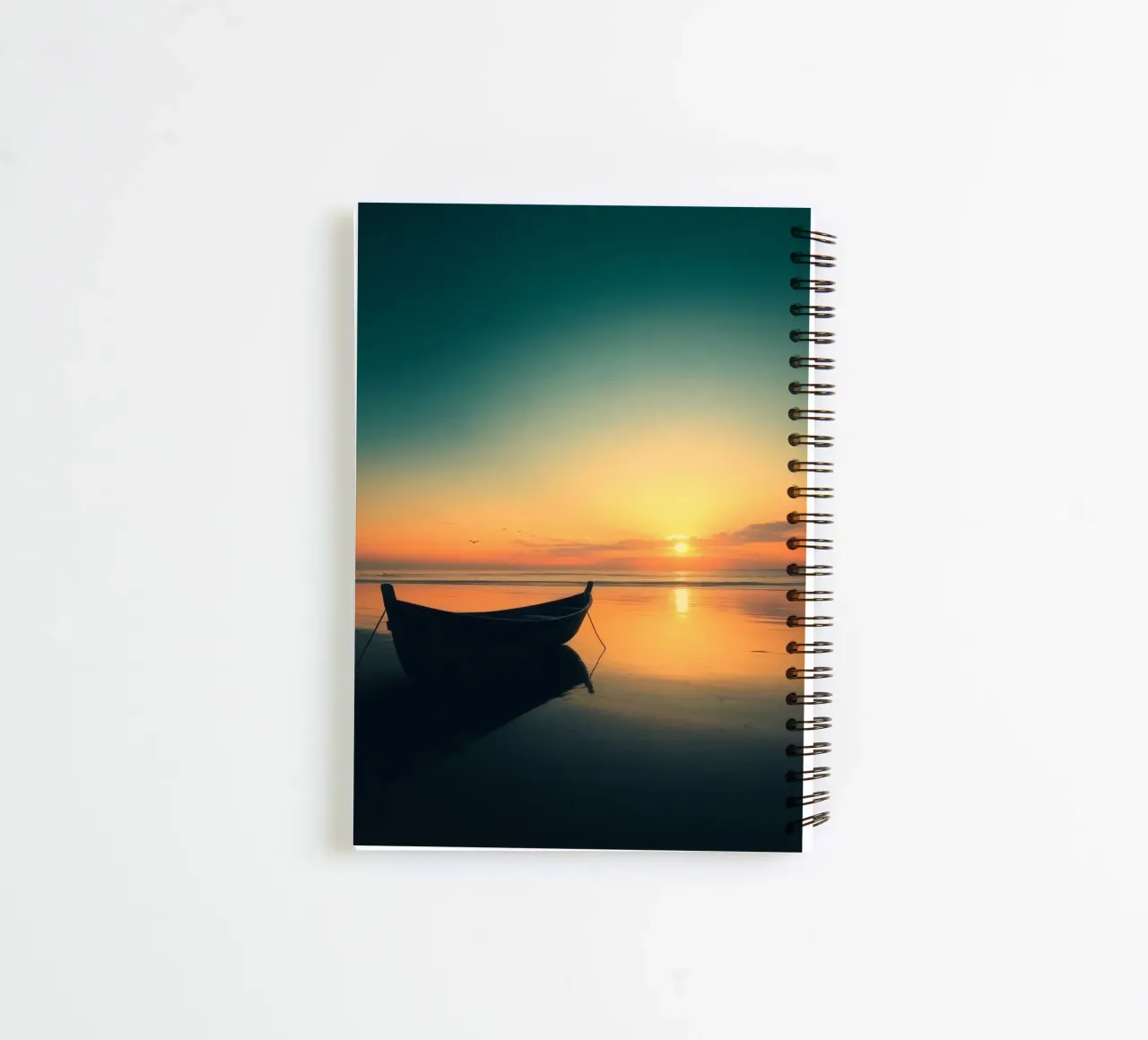 Silhouetted boat resting on calm water at sunset with vibran spiral notebook by DesignDoodle