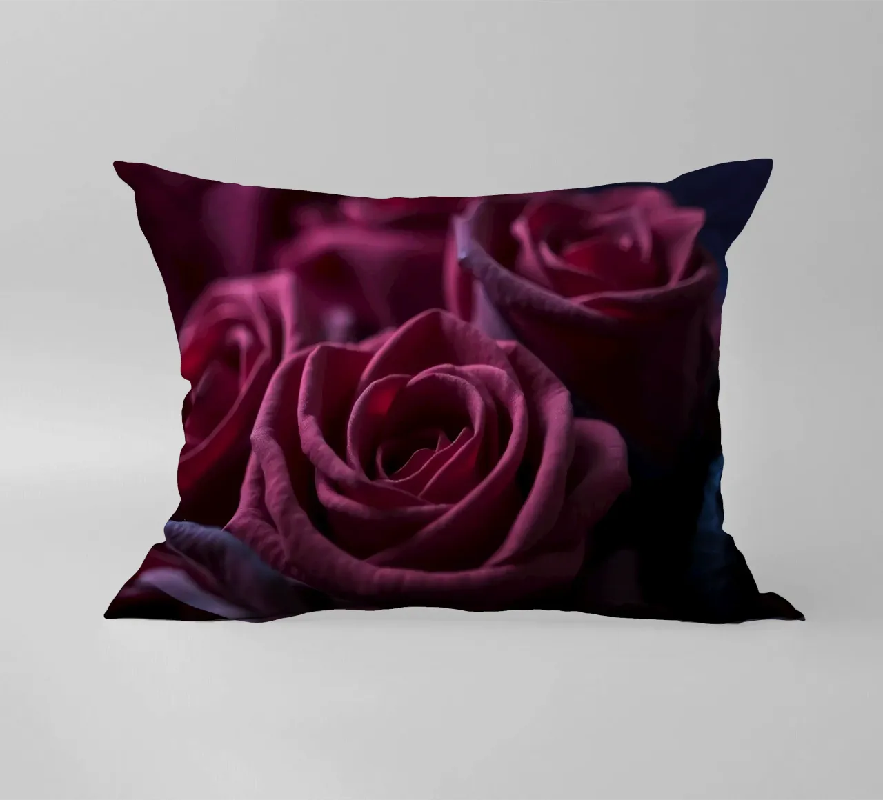 Bouquets of deep red roses arranged artfully in low light decorative cushion by DesignDoodle