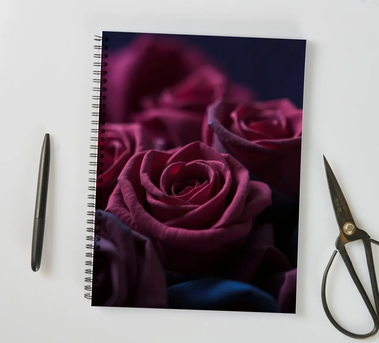 Bouquets of deep red roses arranged artfully in low light spiral notebook by DesignDoodle