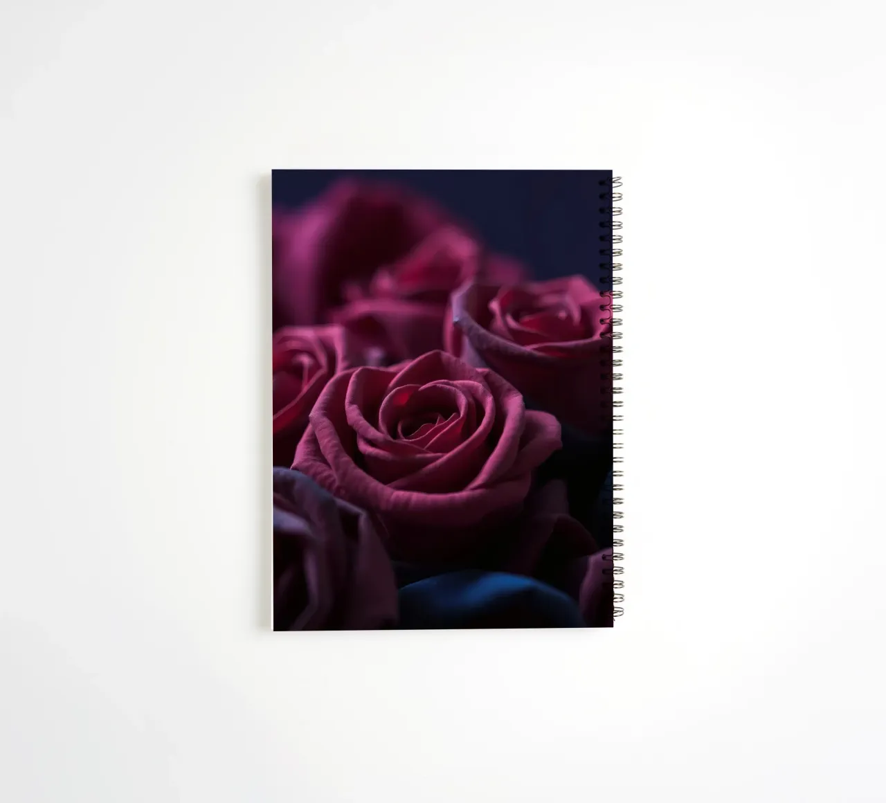 Bouquets of deep red roses arranged artfully in low light spiral notebook by DesignDoodle