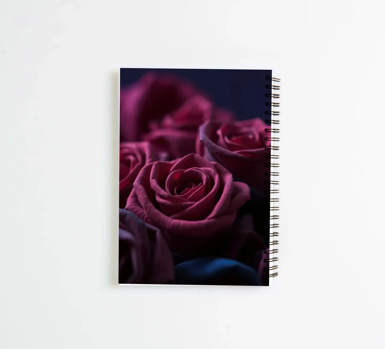 Bouquets of deep red roses arranged artfully in low light spiral notebook by DesignDoodle