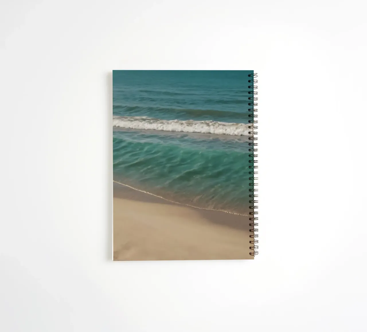 Waves gently lap the sandy shore on a bright sunny day spiral notebook by DesignDoodle