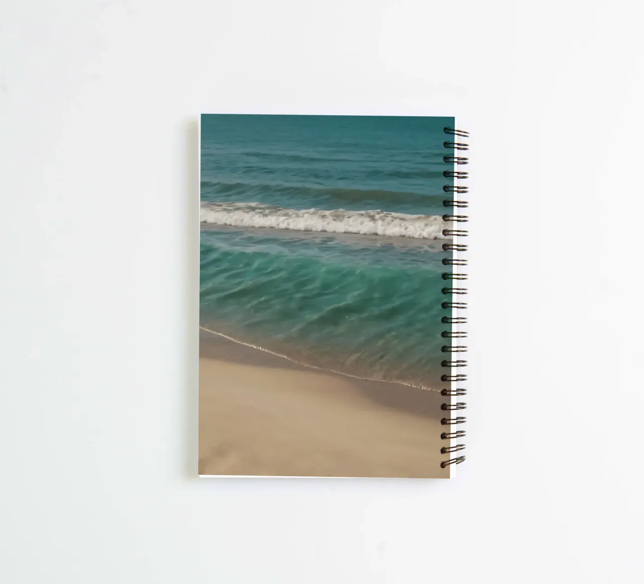 Waves gently lap the sandy shore on a bright sunny day spiral notebook by DesignDoodle