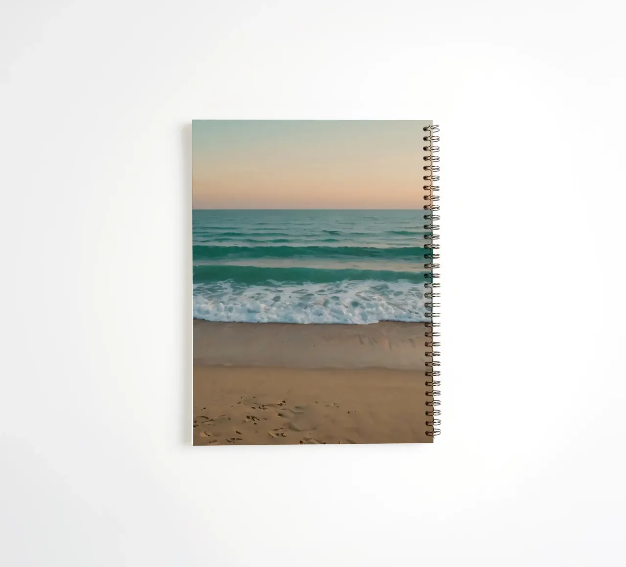Soft waves lap against golden sand under a colorful sky spiral notebook by DesignDoodle
