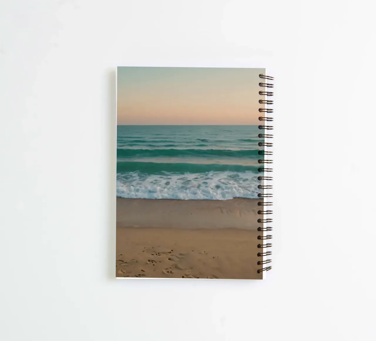 Soft waves lap against golden sand under a colorful sky spiral notebook by DesignDoodle