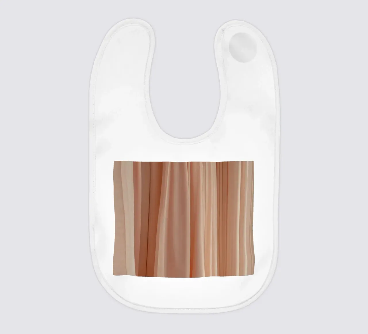 Soft peach fabric drapes elegantly in natural light baby bib by DesignDoodle