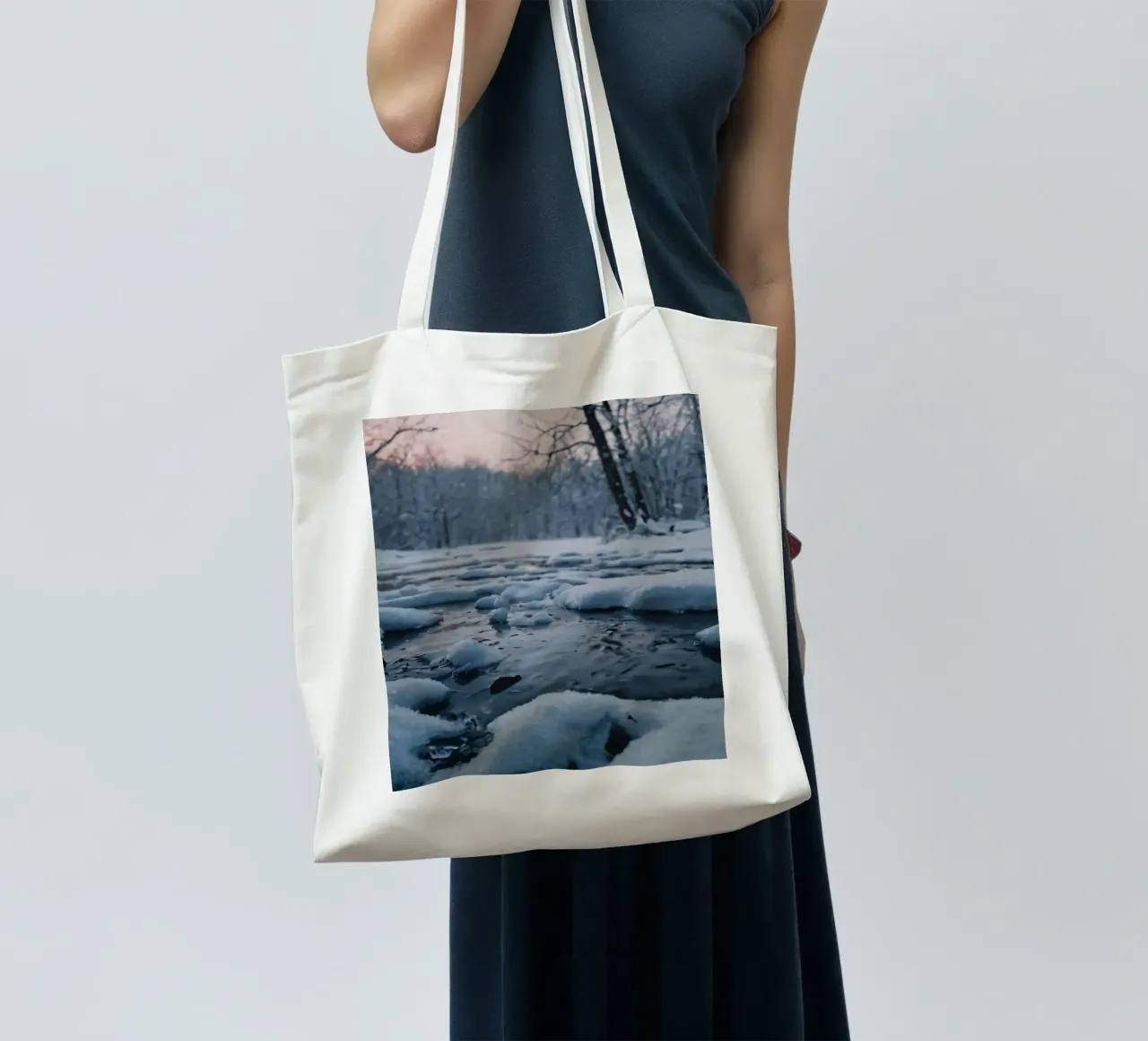 Serene winter landscape with flowing water surrounded snow tote bag by DesignDoodle