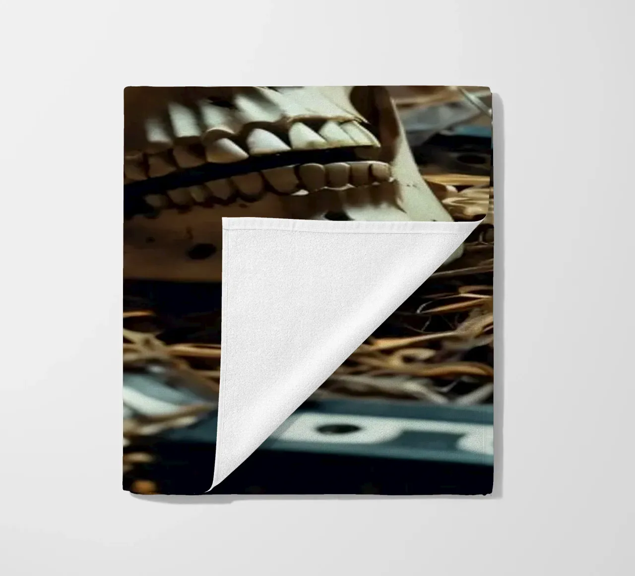 Un teschio che riposa tra vecchie cassette su un letto di paglia telo mare da DesignDoodle