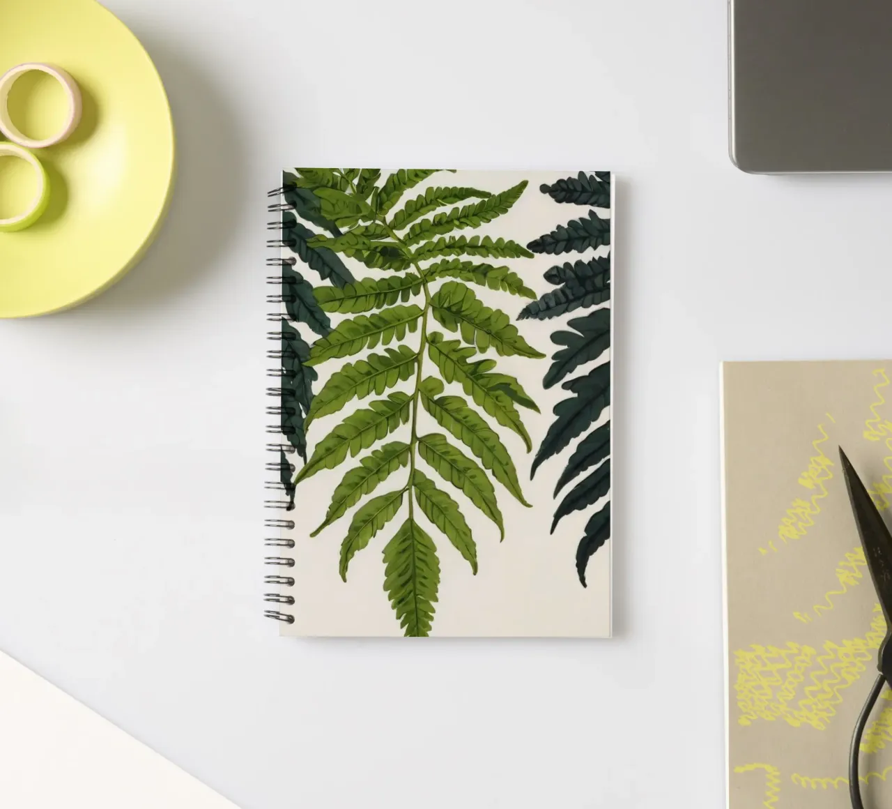 Vibrant green ferns displayed artfully against neutral spiral notebook by DesignDoodle