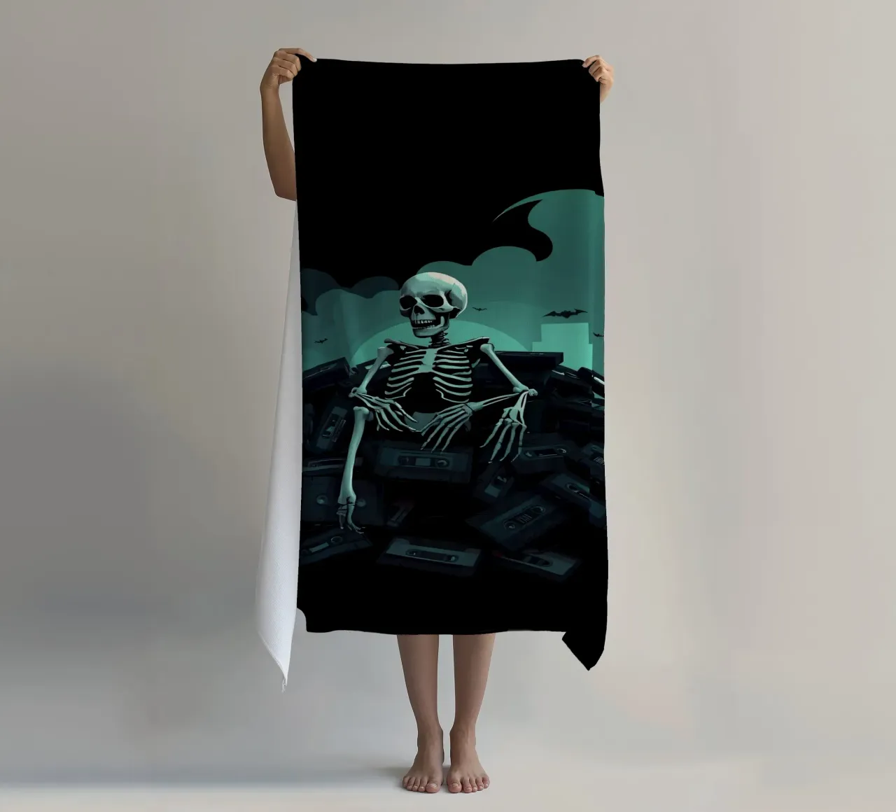 Uno scheletro siede tra vecchie cassette in un'atmosfera spettrale telo mare da DesignDoodle