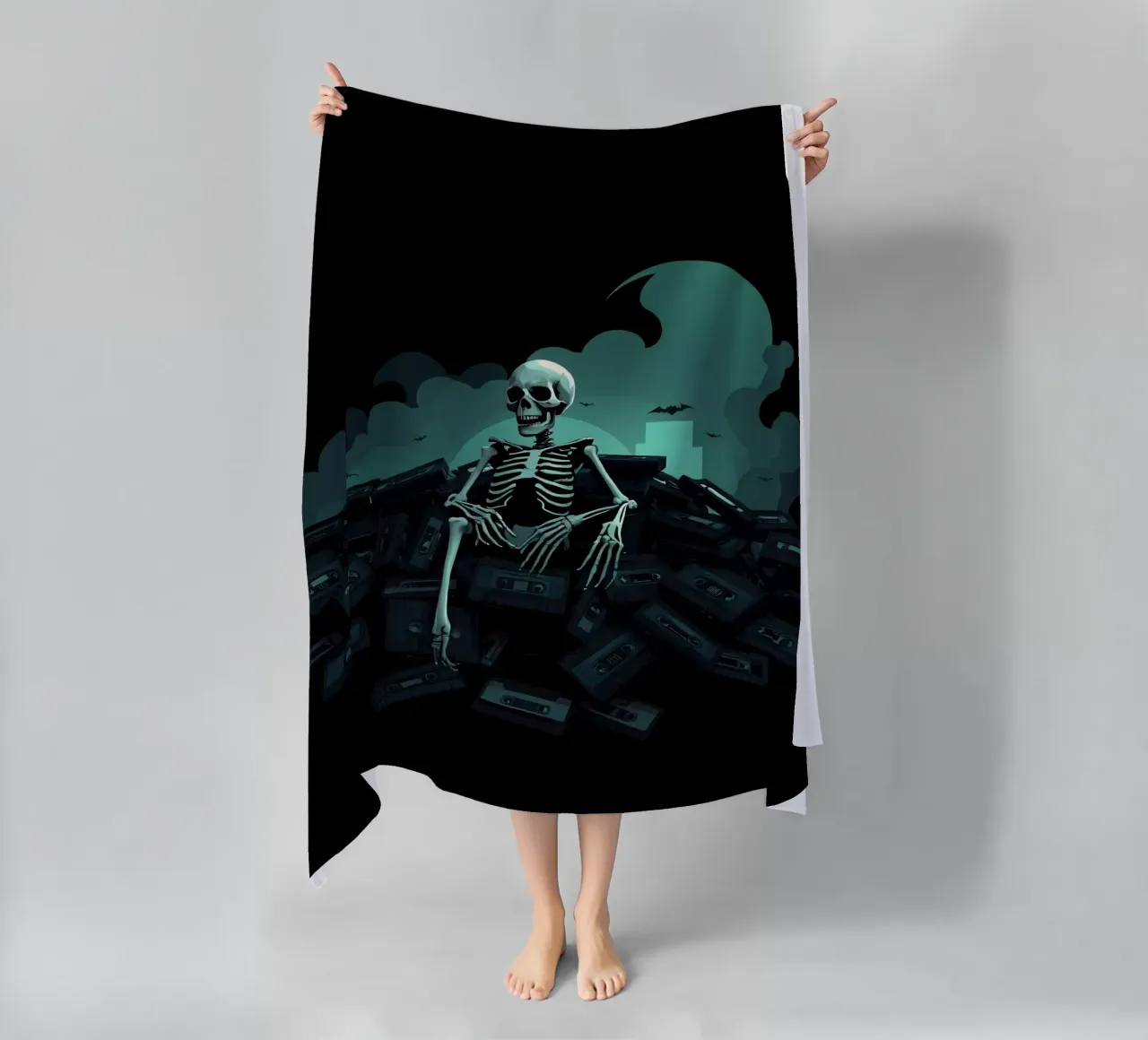 Uno scheletro siede tra vecchie cassette in un'atmosfera spettrale telo mare da DesignDoodle