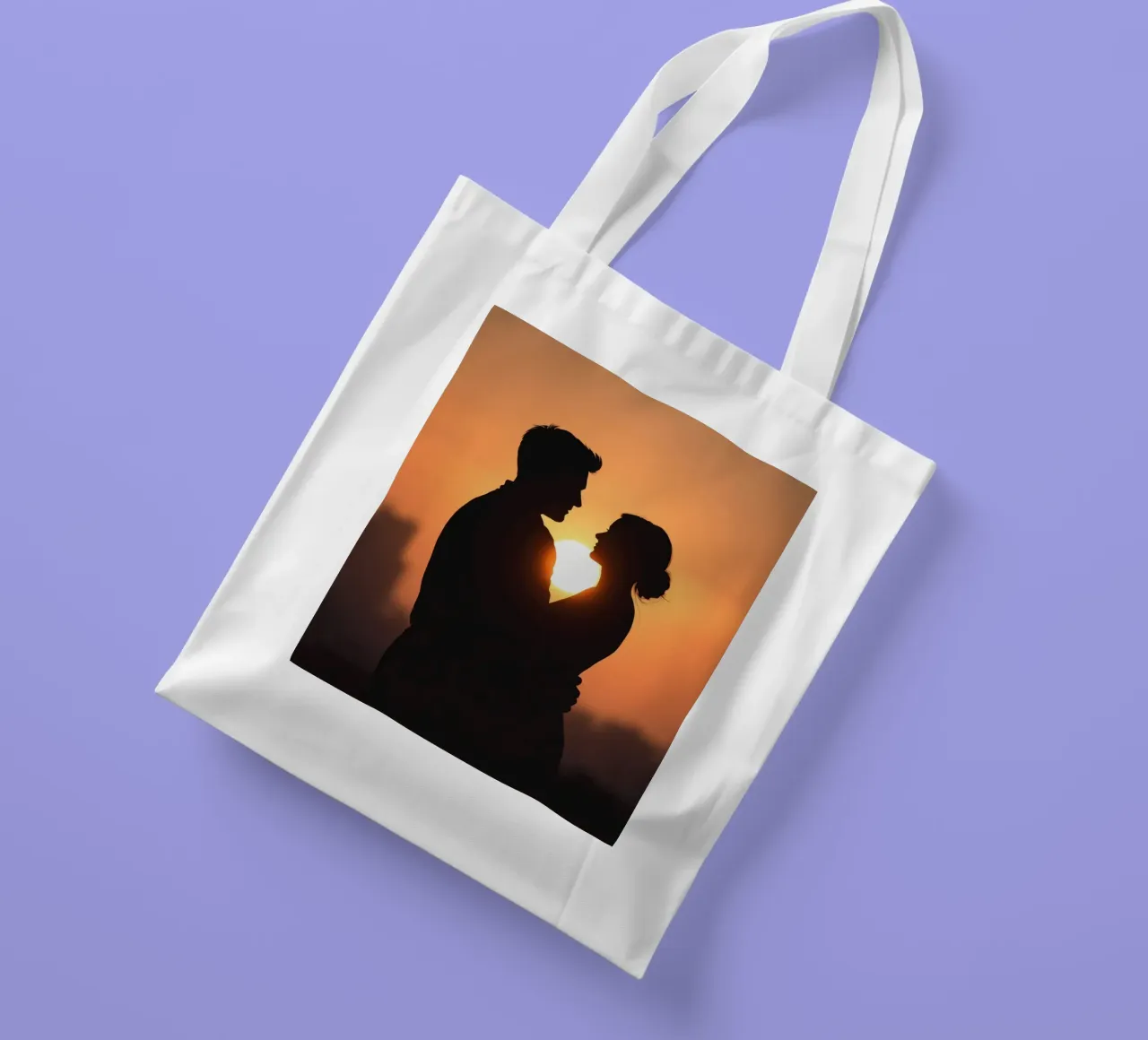 Una pareja se abraza durante una puesta de sol silueteada tote bag de DesignDoodle
