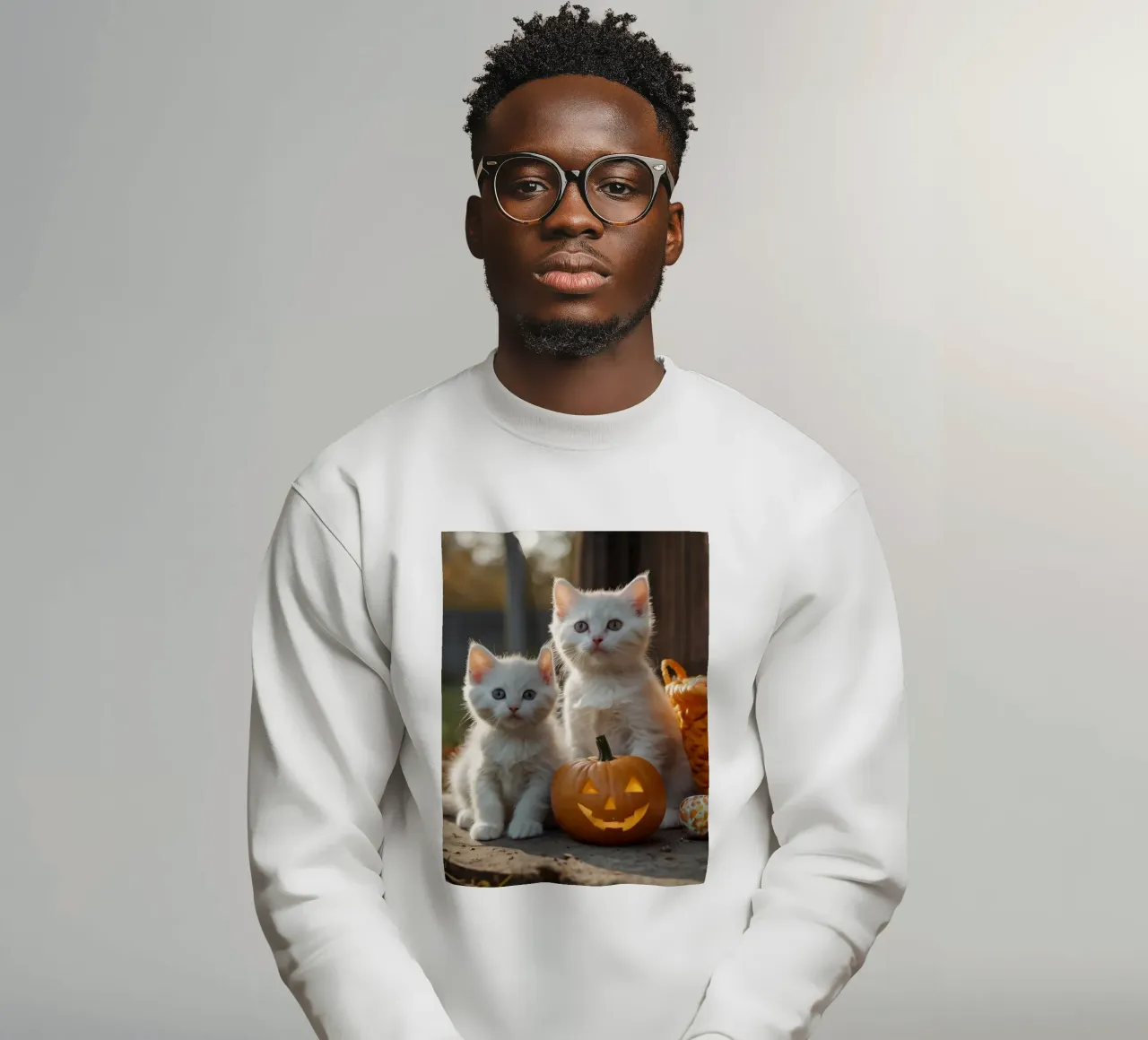 Due gattini giocherelloni accanto a zucche intagliate e a un cestino felpa da DesignDoodle