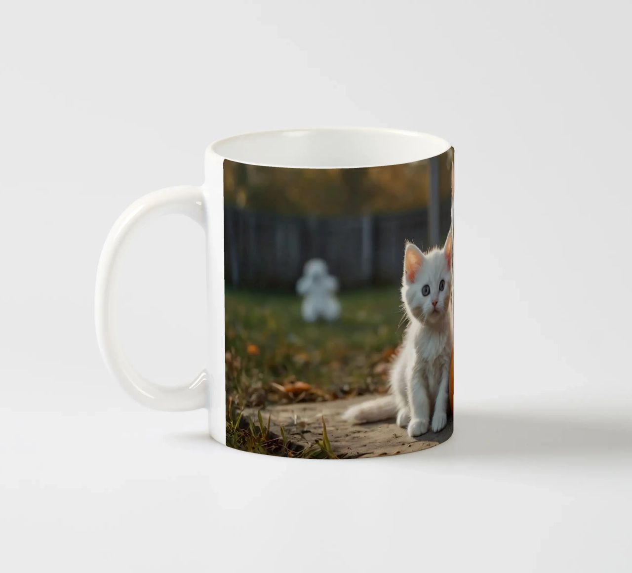 Due gattini giocherelloni accanto a zucche intagliate e a un cestino tazza in ceramica da DesignDoodle