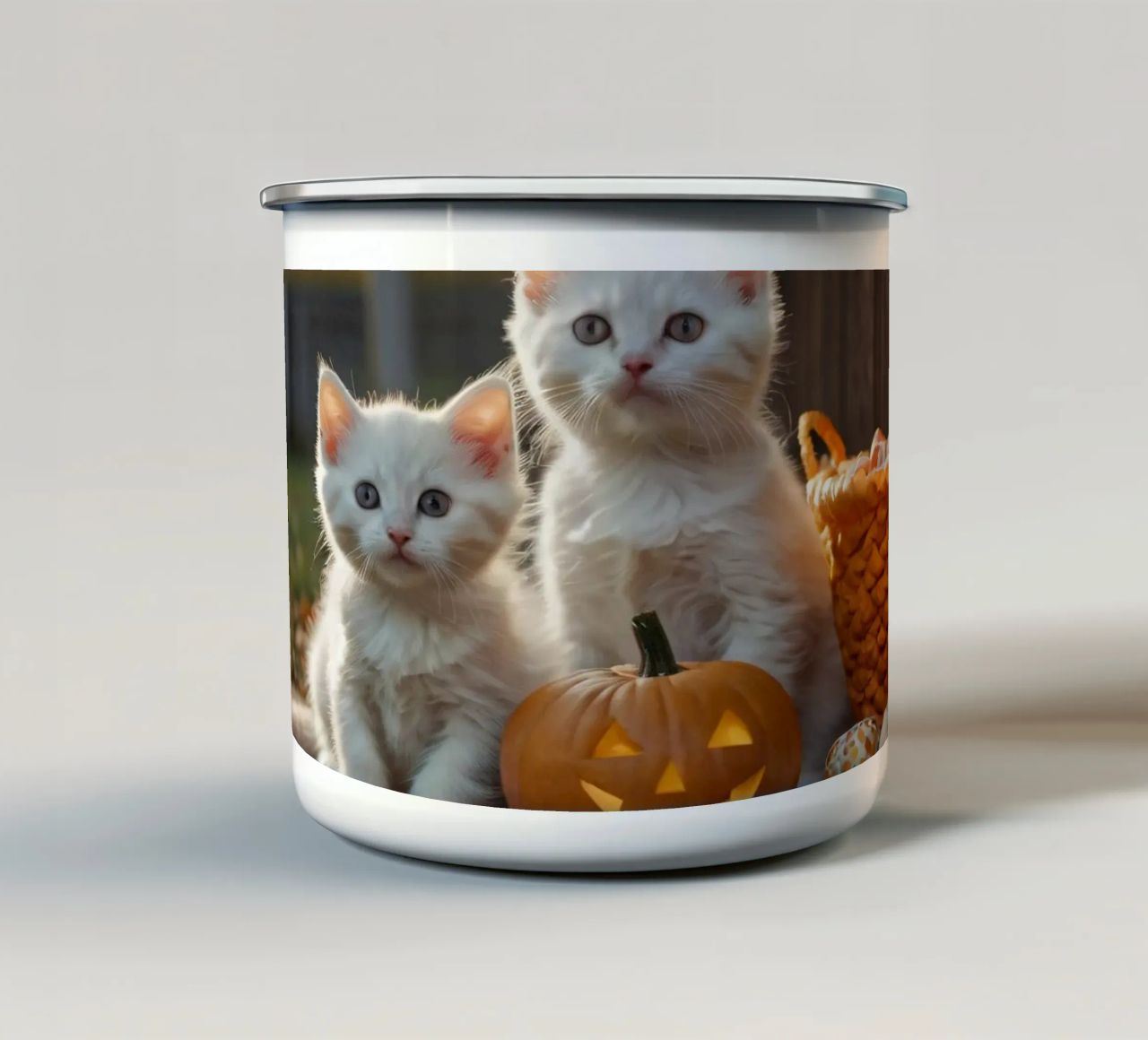 Due gattini giocherelloni accanto a zucche intagliate e a un cestino tazza in smalto da DesignDoodle