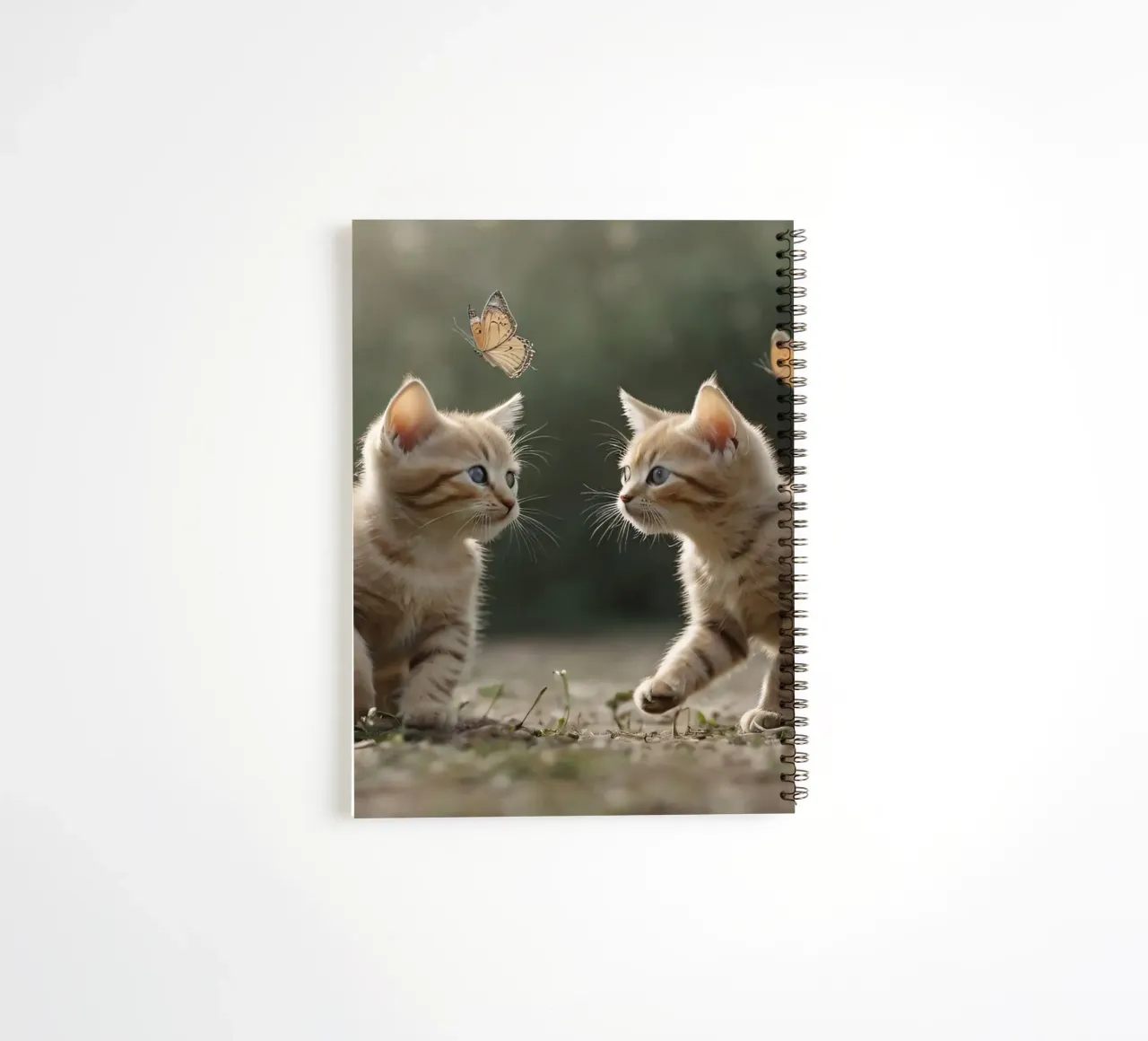 Two playful kittens chase butterflies in a sunlit garden spiral notebook by DesignDoodle