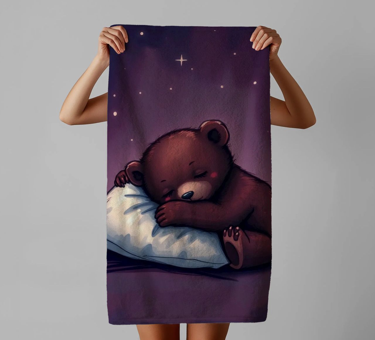 Un mignon ours brun câline un oreiller sous un ciel étoilé serviette de bain de DesignDoodle
