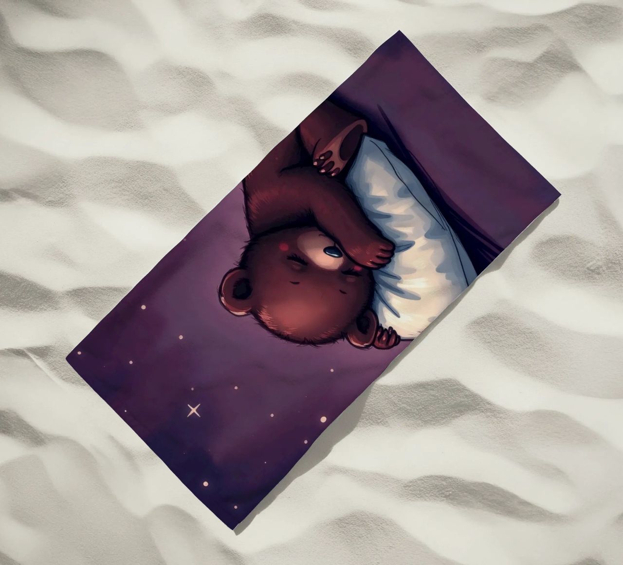 Un mignon ours brun câline un oreiller sous un ciel étoilé serviette de plage de DesignDoodle