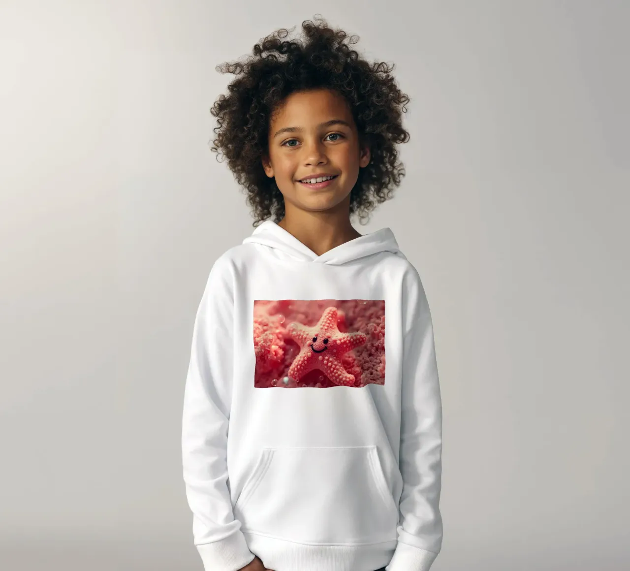 Étoile de mer corail brillant avec un visage souriant reposant sur du rose sweat à capuche enfant de DesignDoodle