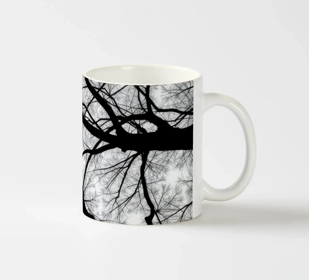Des branches sans vie s'étendent sur un ciel nuageux mug en céramique de DesignDoodle