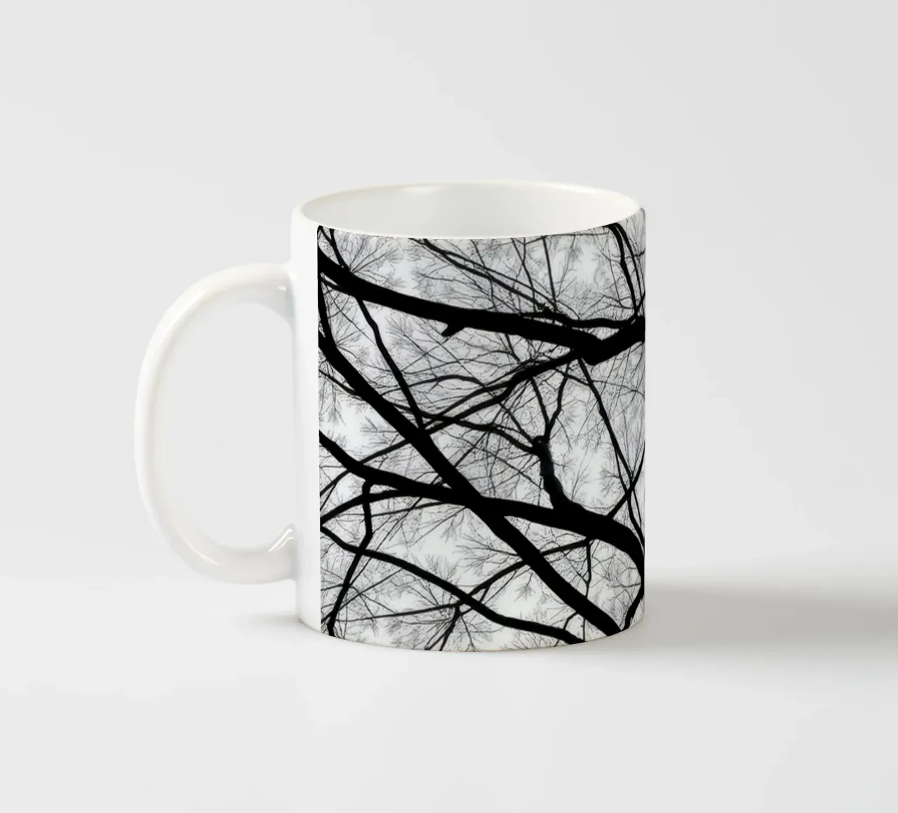 Des branches sans vie s'étendent sur un ciel nuageux mug en céramique de DesignDoodle