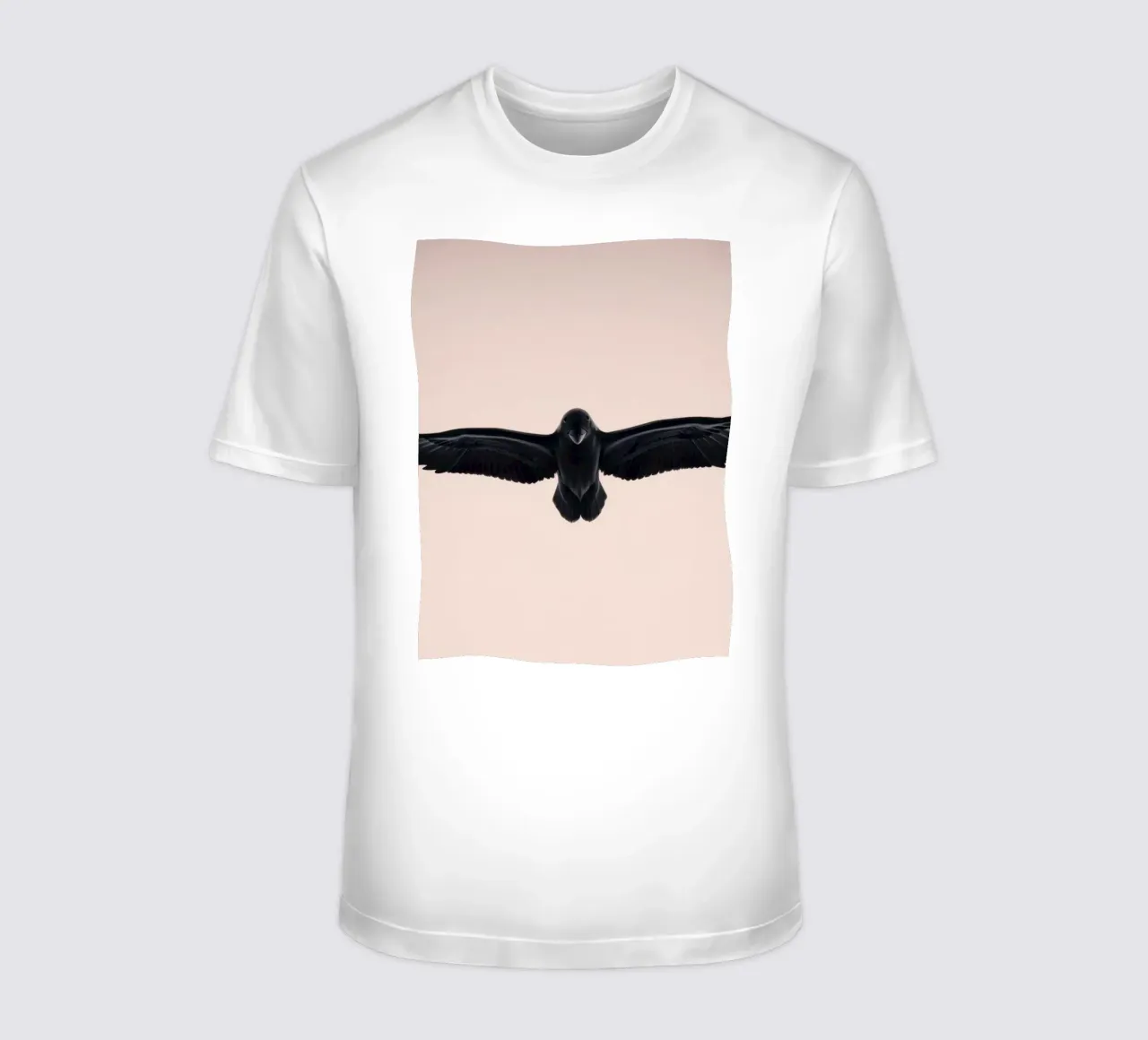 Majestic black bird soaring against a soft pastel sky t-shirt by DesignDoodle