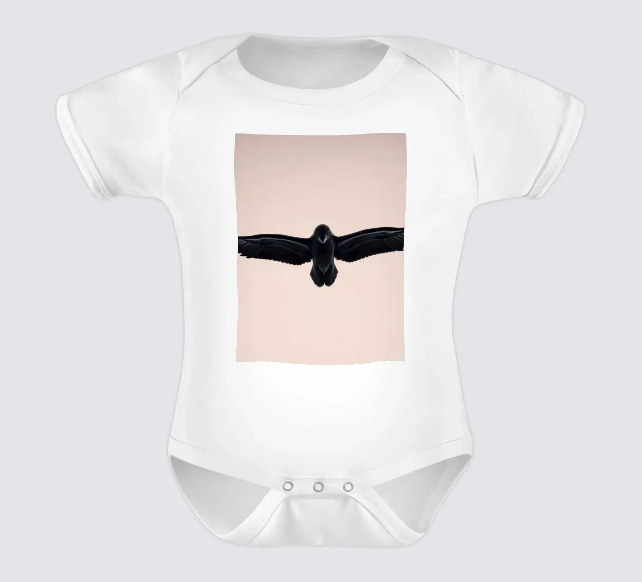 Majestueux oiseau noir s'élevant dans un ciel doux et pastel body bébé de DesignDoodle