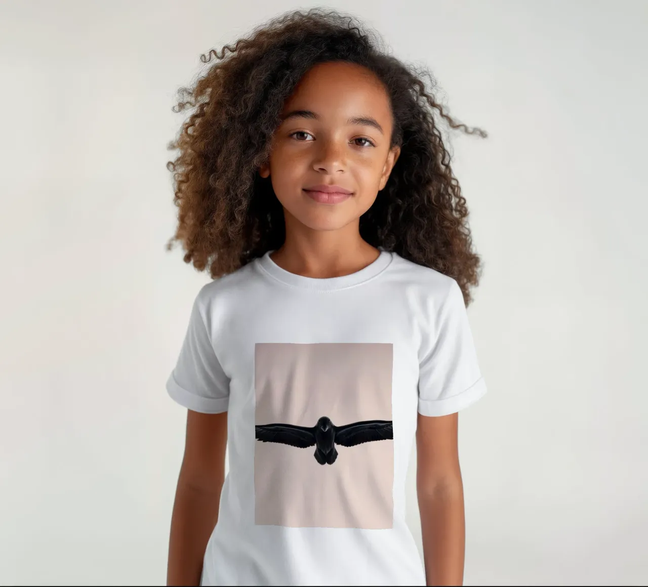 Maestoso uccello nero che si libra in un morbido cielo pastello t-shirt bambini da DesignDoodle