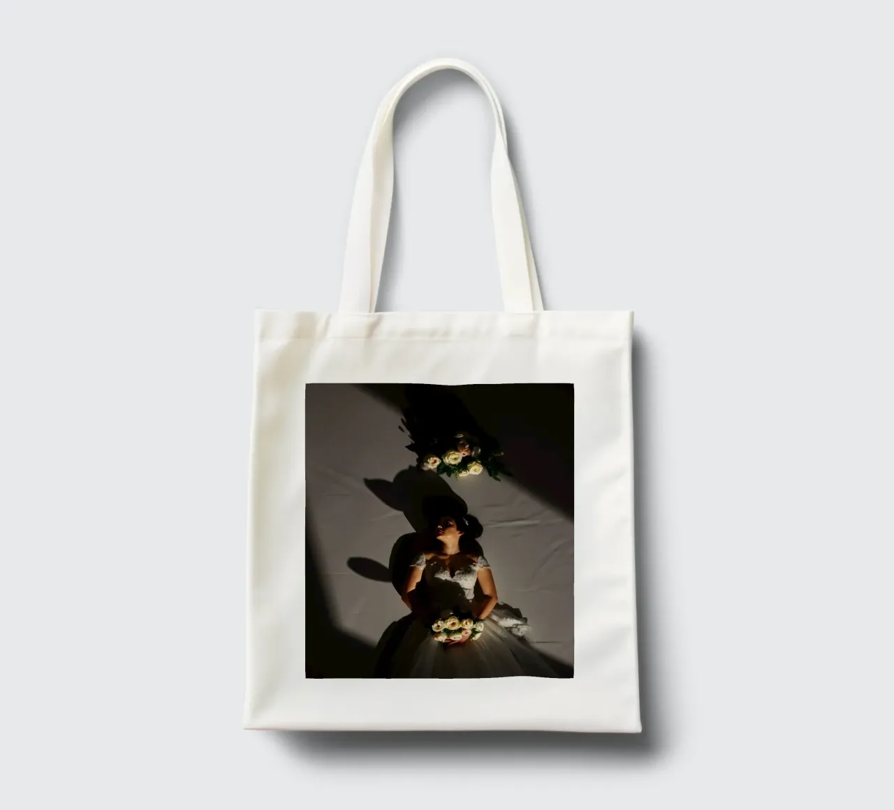 La mariée, vêtue d'une robe élégante, prend une pose dramatique sous un éclairage doux. tote bag de DesignDoodle