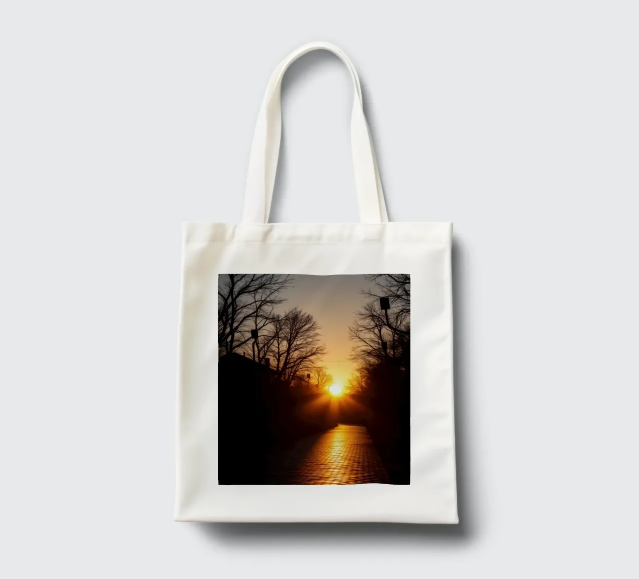 Sunset view along a tree-lined pathway with warm hues tote bag by DesignDoodle