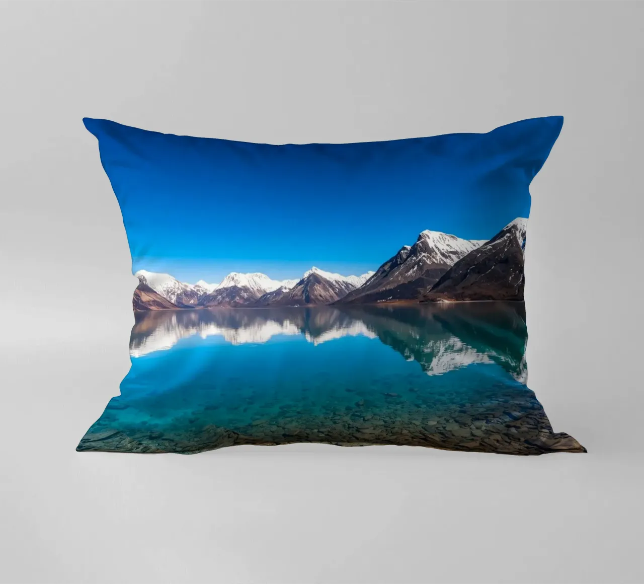 view of a serene lake surrounded by snow-capped mountains decorative cushion by DesignDoodle
