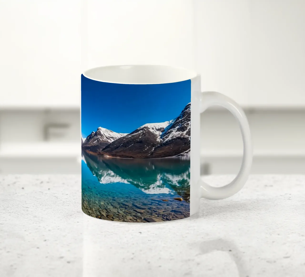 view of a serene lake surrounded by snow-capped mountains ceramic mug by DesignDoodle