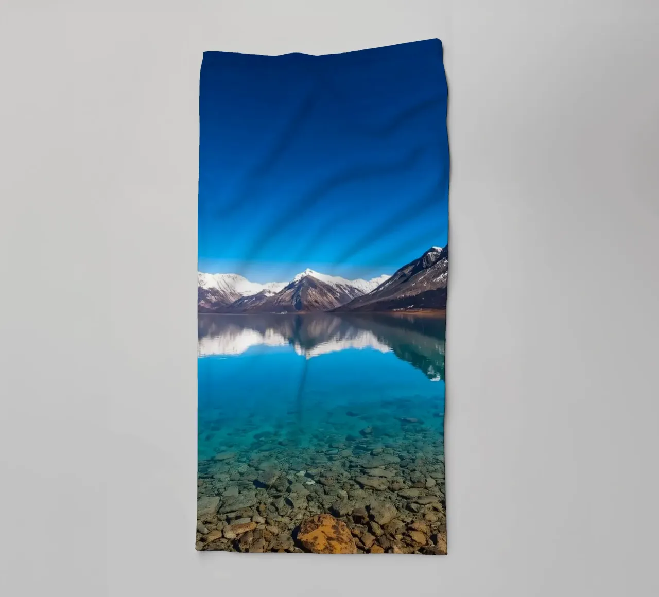 view of a serene lake surrounded by snow-capped mountains towel by DesignDoodle