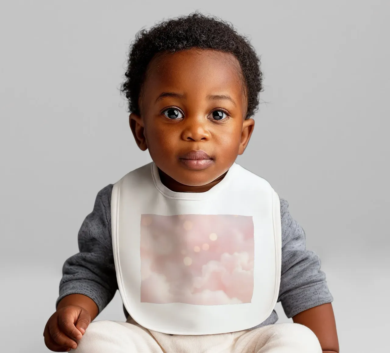 Soft pink abstract background with fluffy clouds and gentle baby bib by DesignDoodle