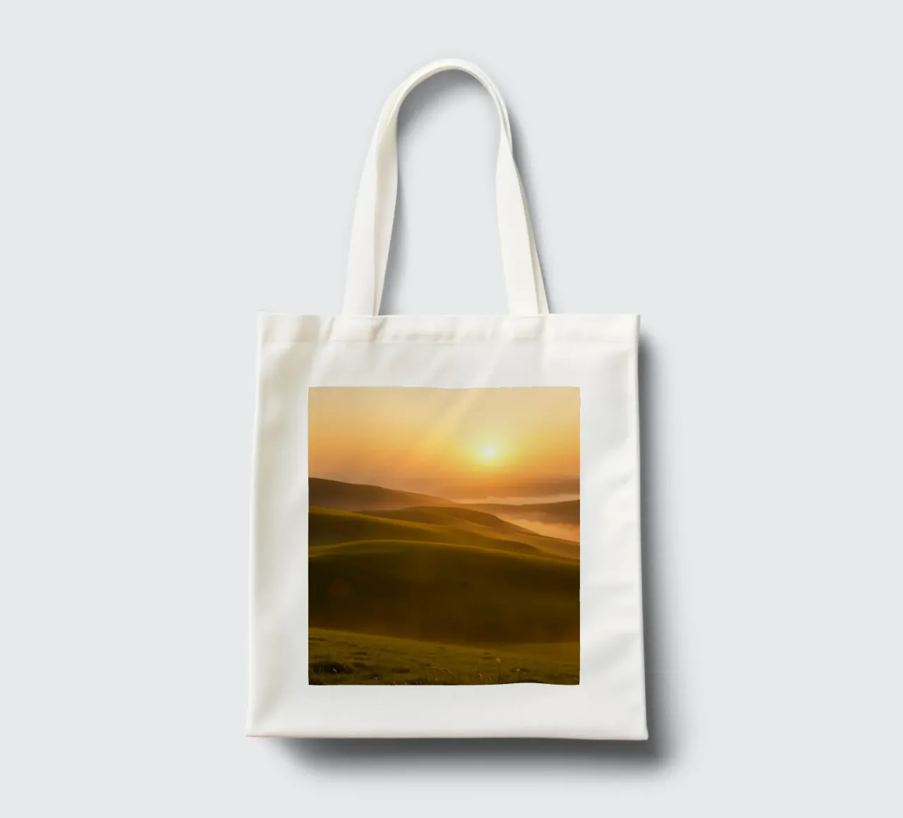 Sunset over rolling green hills with mist creating a serene tote bag by DesignDoodle