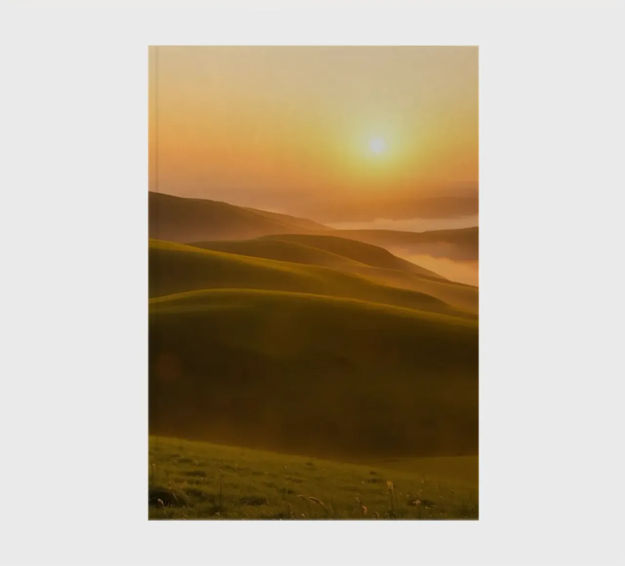 Sunset over rolling green hills with mist creating a serene notebook by DesignDoodle