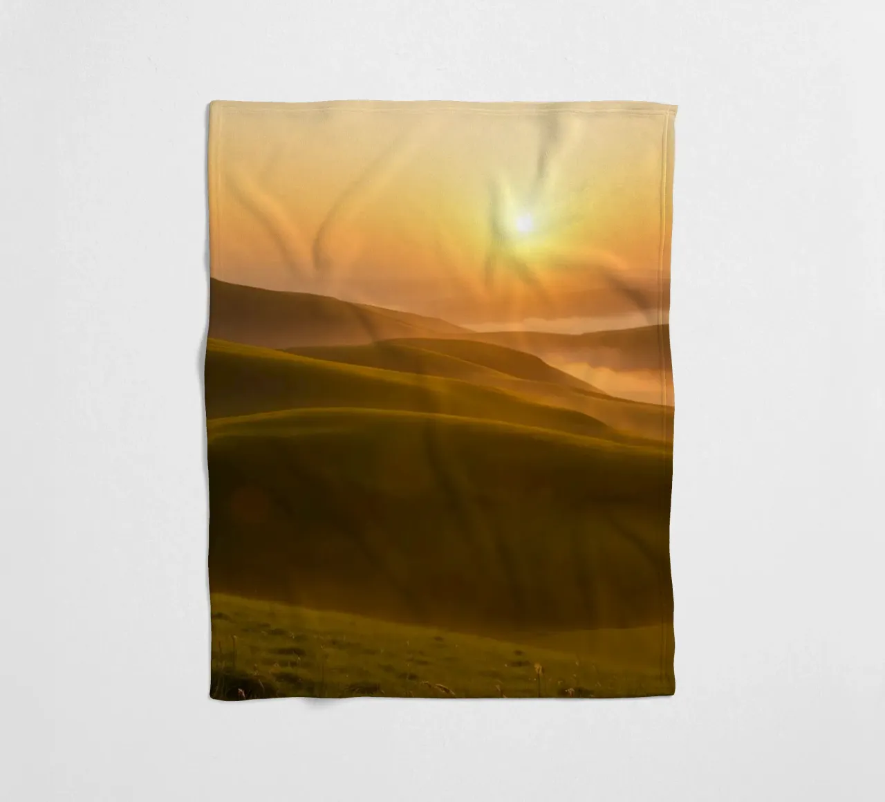 Sunset over rolling green hills with mist creating a serene fleece blanket by DesignDoodle