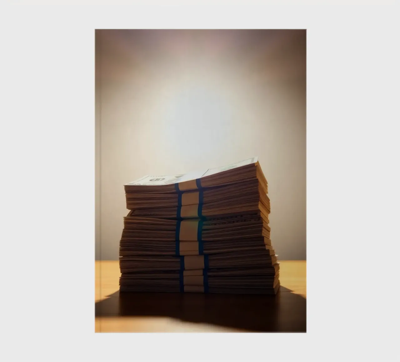 Stacked currency bundles illuminated by soft glow in a dimly notebook by DesignDoodle