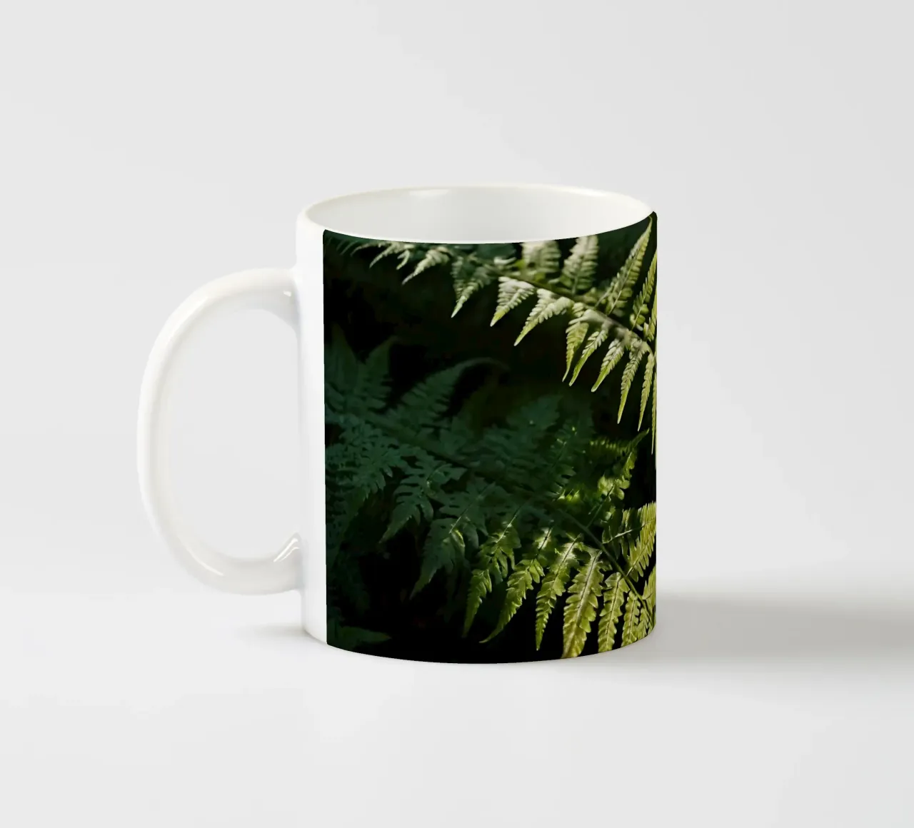 Sunlight filters through lush green ferns in a tranquil fore ceramic mug by DesignDoodle