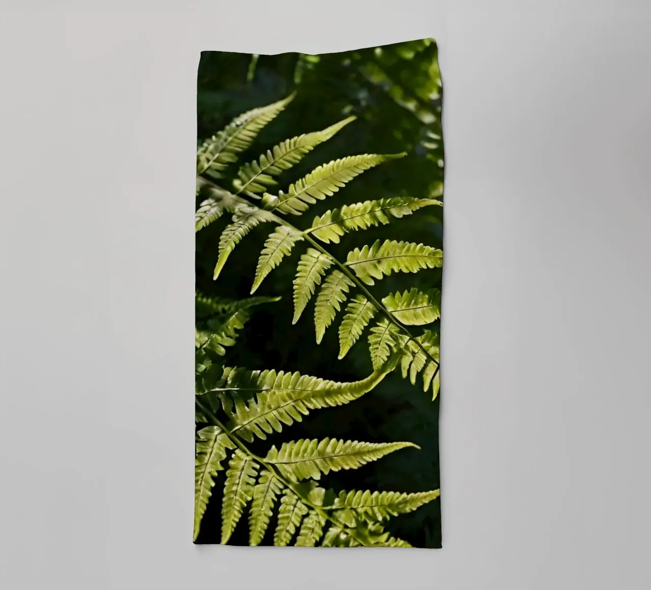 Sunlight filters through lush green ferns in a tranquil fore towel by DesignDoodle