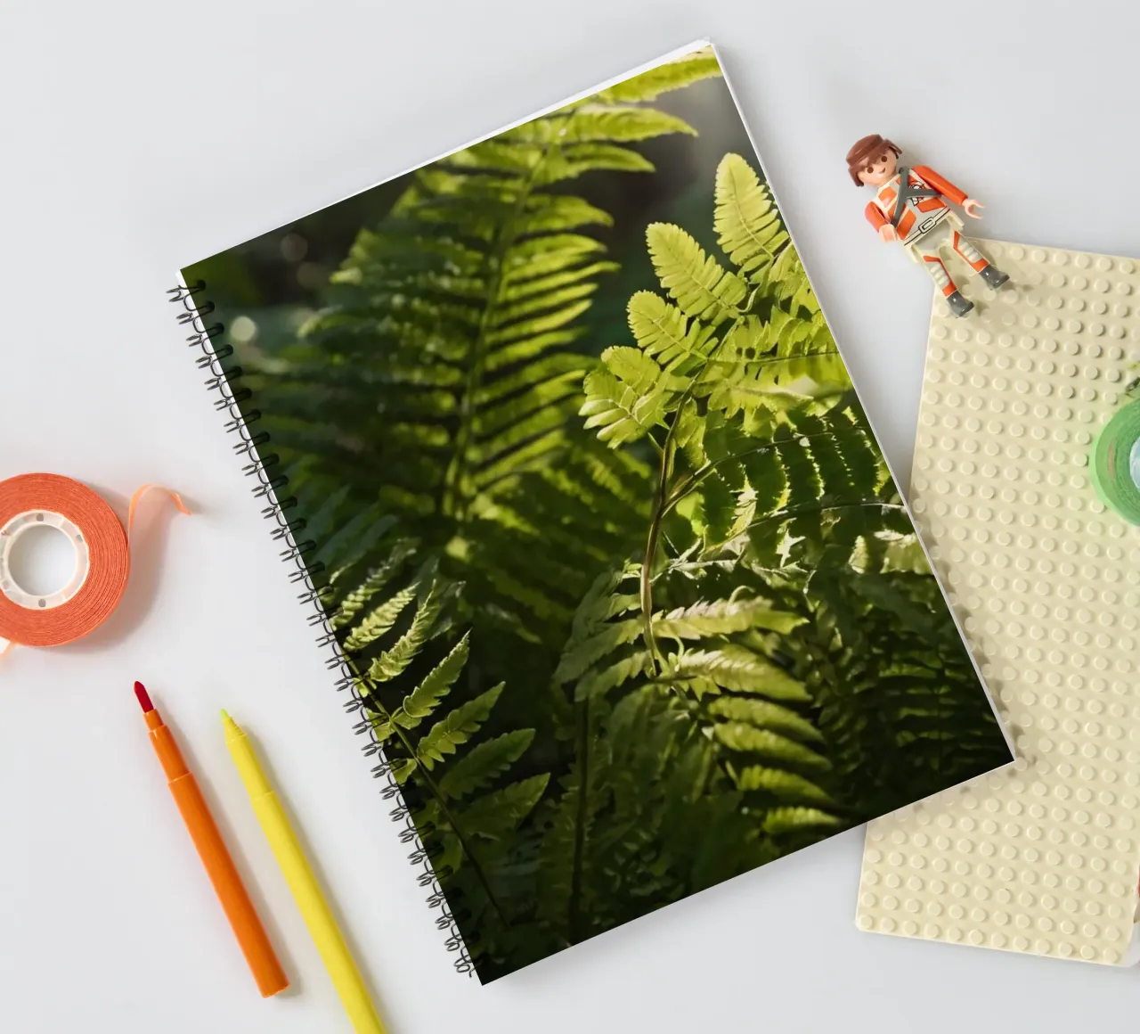 Lush green ferns basking in soft sunlight in a serene forest spiral notebook by DesignDoodle