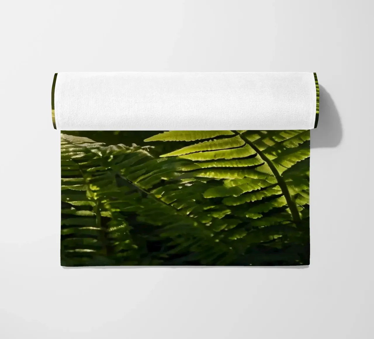 Felci verdi e rigogliose illuminate dalla luce del sole in una fitta foresta telo mare da DesignDoodle