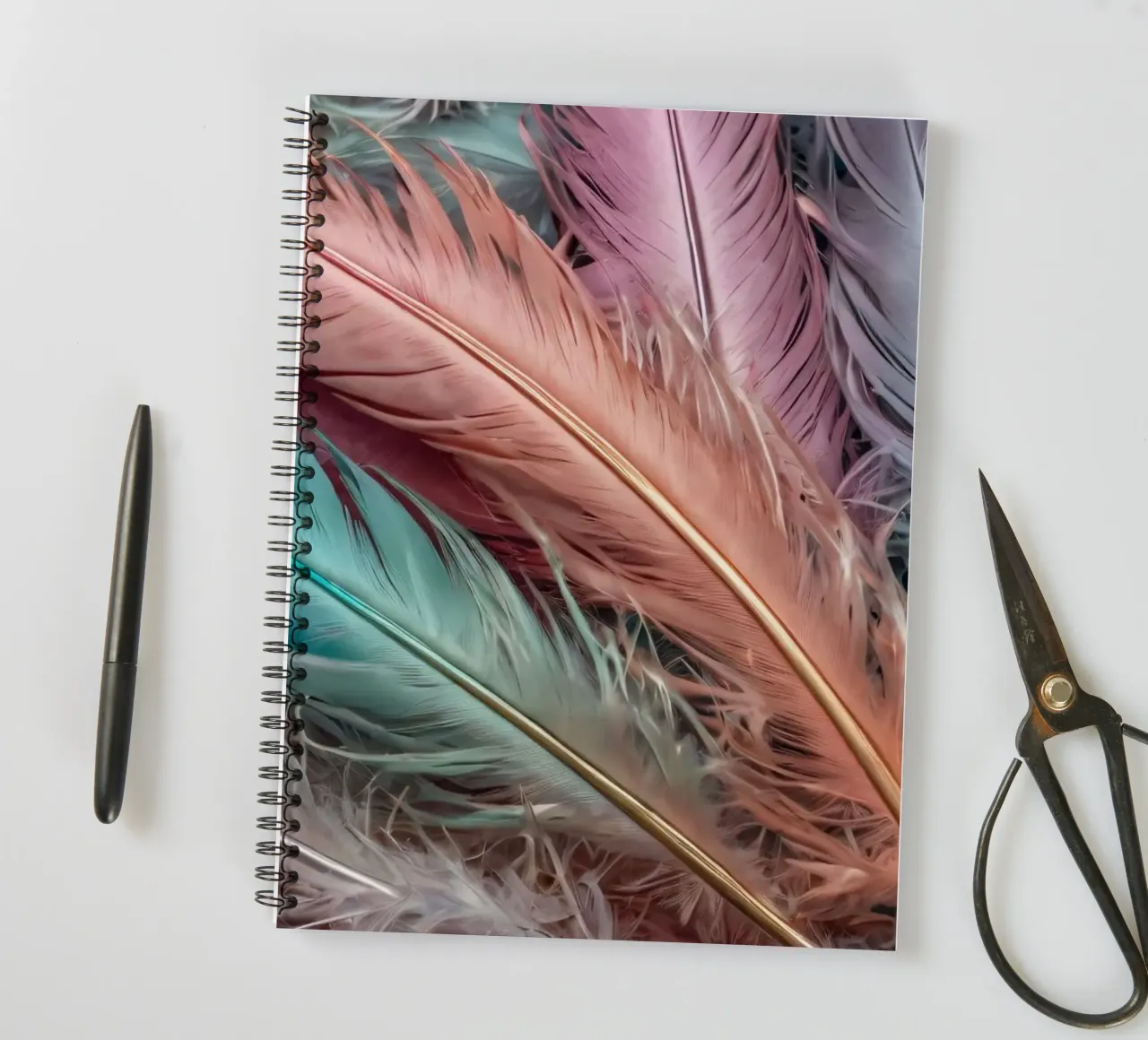 Colorful feathers arranged in a vibrant pattern with pastel spiral notebook by DesignDoodle