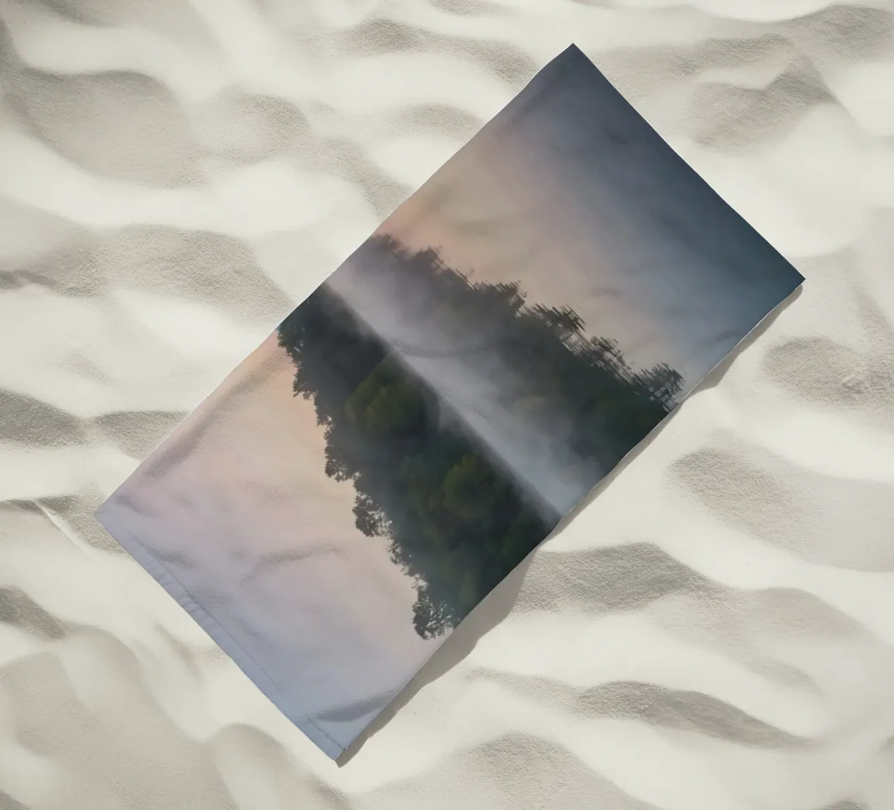 mist rises over a tranquil lake surrounded by lush trees beach towel by DesignDoodle