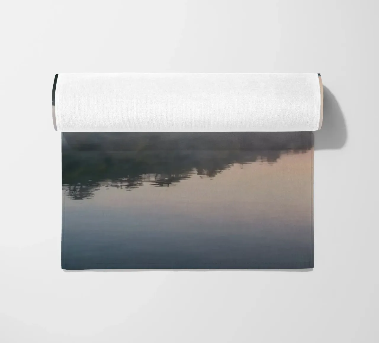 mist rises over a tranquil lake surrounded by lush trees beach towel by DesignDoodle